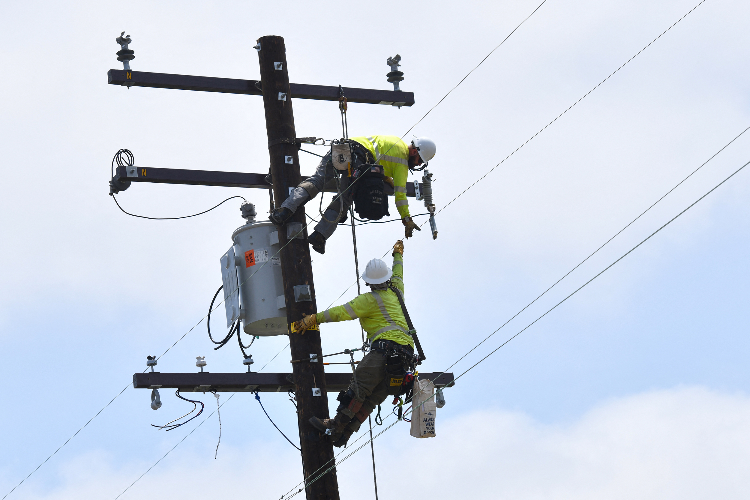 Utility workers on power lines — the grid you're paying for